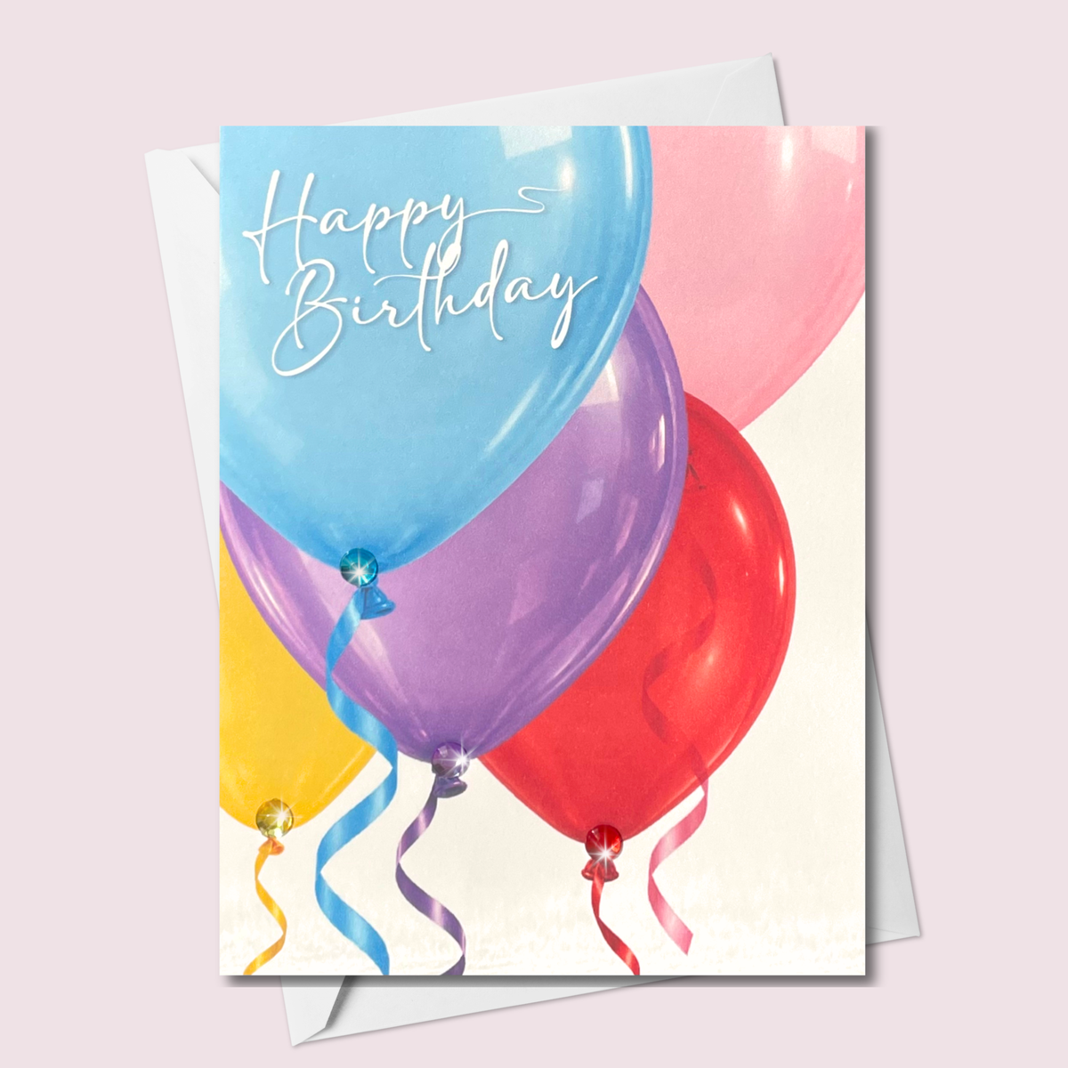 Russell Jeffrey Design greeting card featuring colourful balloons with Happy Birthday Script, curling ribbons and matching jewel accents, shown with a white envelope.