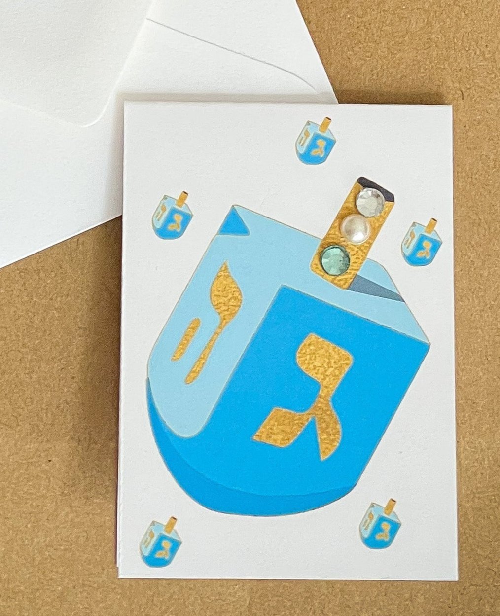 this is a mini note card on a craft paper gift bag with a white envelope and a black marker , the card has a blue dreidel
