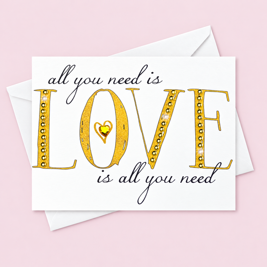 All You Need Is Love  Gold + Crystal greeting card with its original design, shown with a white envelope on a pale pink background