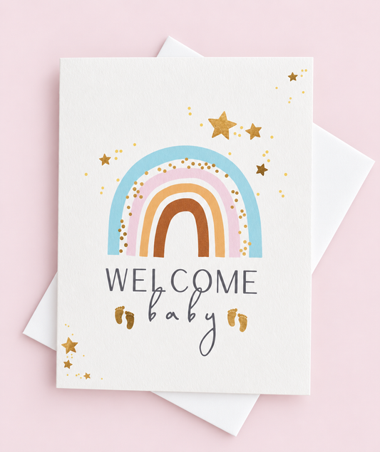 Welcome Baby Rainbow greeting card with its original design, shown with a white envelope on a pale pink background