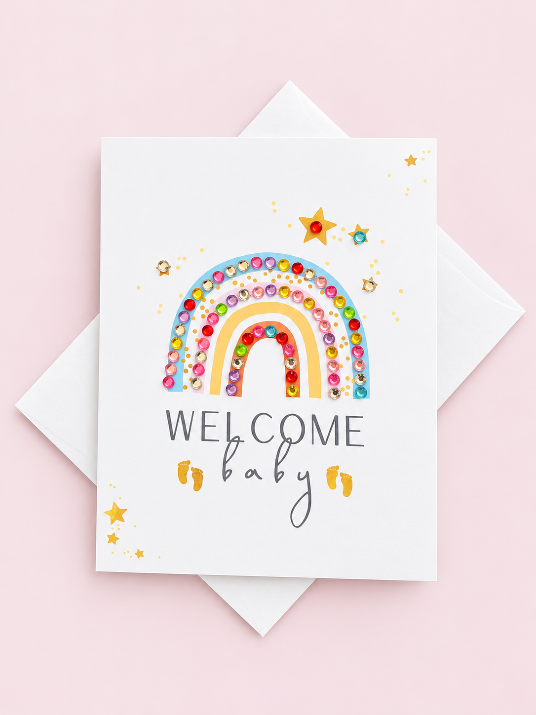 Welcome Baby Rainbow Pastel greeting card with its original design, shown with a white envelope on a pale pink background