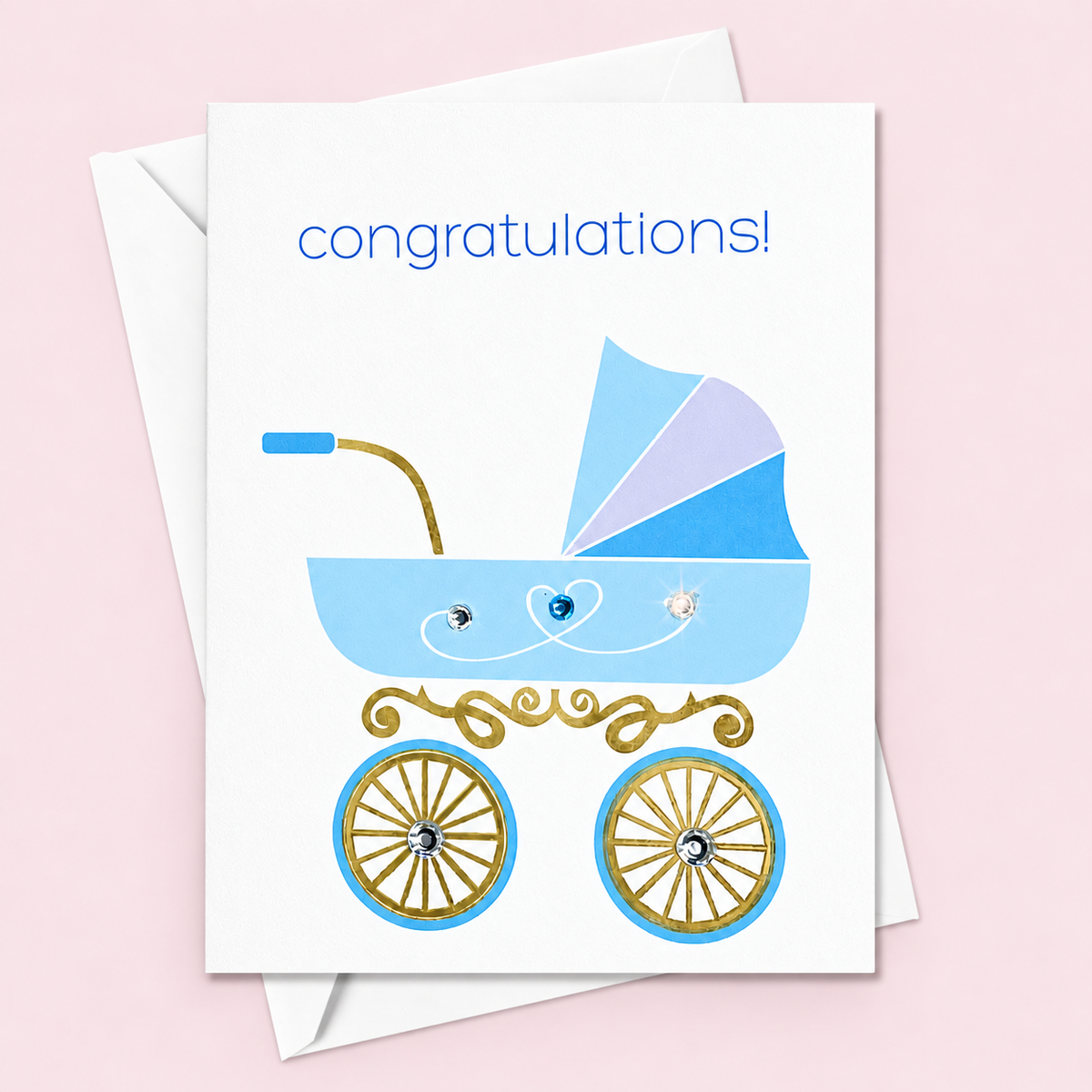 White congratulations card with a blue stroller and sparkling details, with a white envelope on a pale pink background.