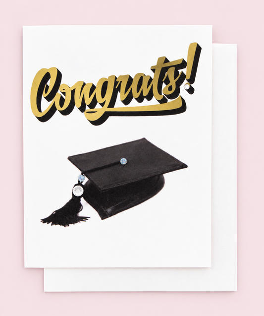Congrats! Graduation Greeting Card – Black Cap & Gold Lettering – Blank Inside with white envelope on a pale pink background