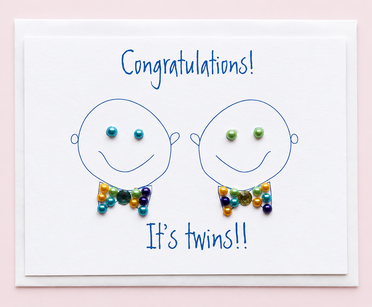 Congratulations Its Twin Boys greeting card with hand-applied sparkling details with a white envelope on pale pink