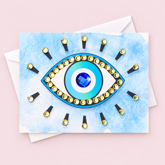Evil Eye Protection on Blue Watercolour Background greeting card with its original design, shown with a white envelope on a pale pink background