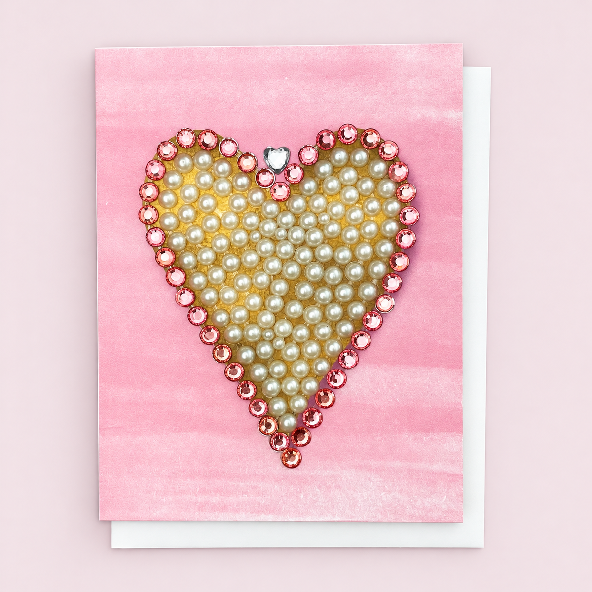 Pink Edged Pearl Heart + Crystal Heart Crown with a white envelope on a pale pink background
