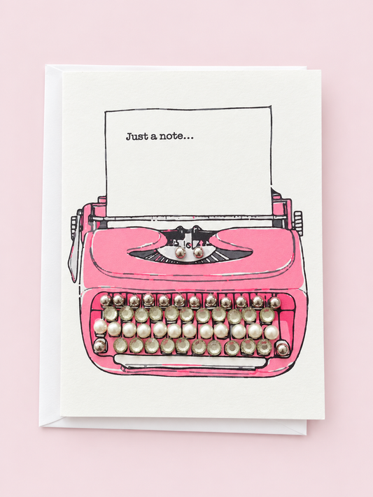 Just a note pink typewriter with a white envelope on a pale pink background