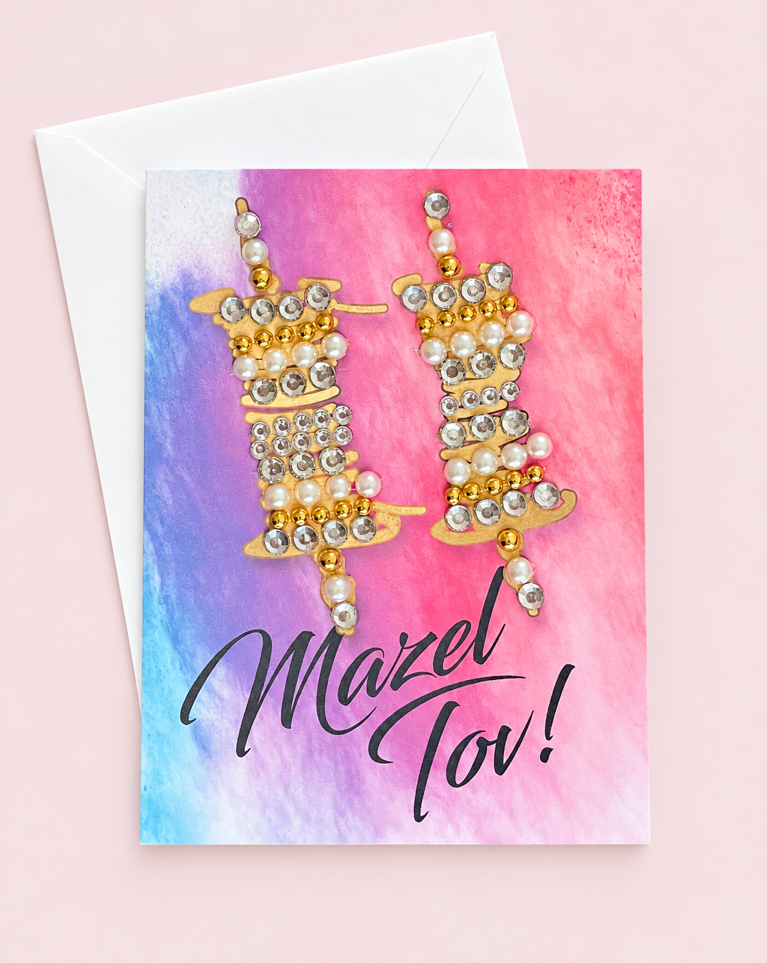 Mazel Tov Bar/Bat Mitzvah Gold Torah Scrolls on Watercolour Background greeting card with its original design, shown with a white envelope on a pale pink background