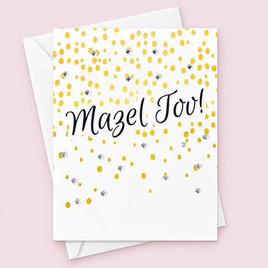 Mazel Tov Gold Confetti Black Font greeting card with its original design, shown with a white envelope on a pale pink background