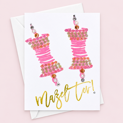 Mazel tov pink scrolls with a white envelope on a pale pink background