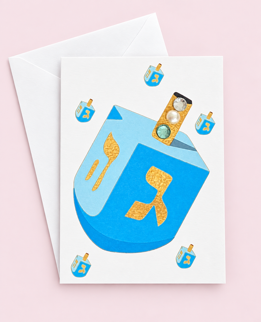 Mini Chanukah Driedel in Blue greeting card with its original design, shown with a white envelope on a pale pink background
