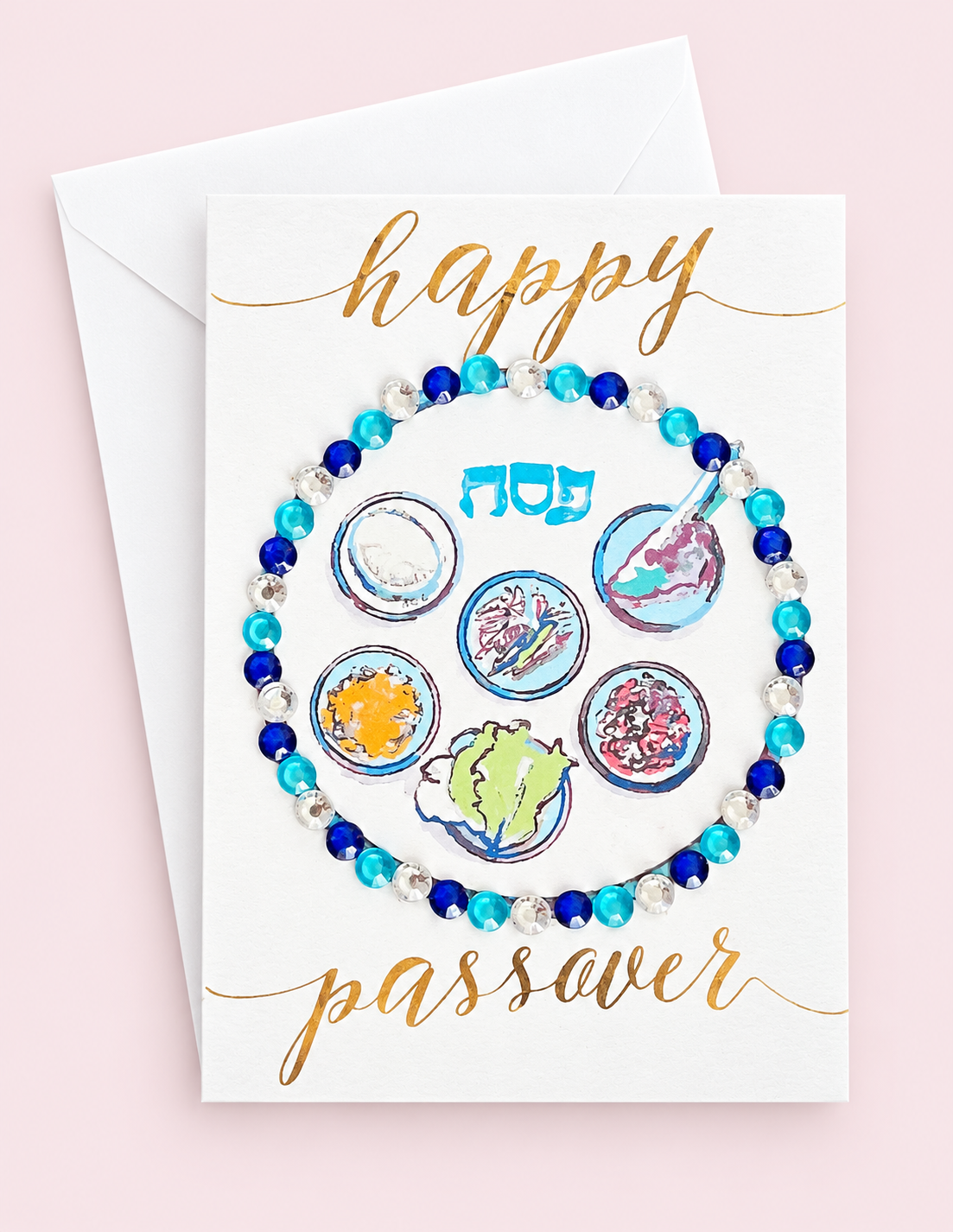 Mini Happy Passover Blue Sedar Plate greeting card with its original design, shown with a white envelope on a pale pink background