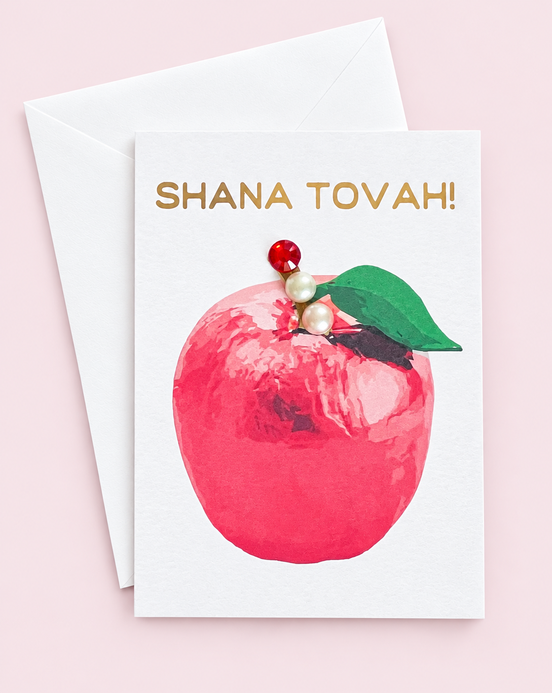Mini Shana Tova Red Apple greeting card with its original design, shown with a white envelope on a pale pink background