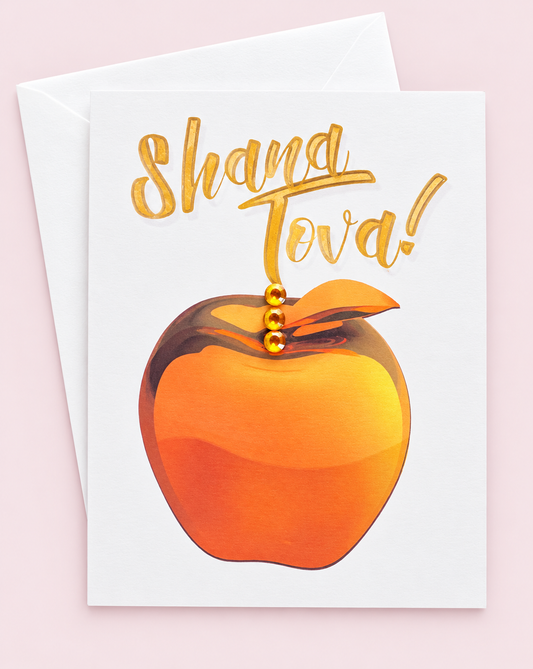 Shana Tova! Gold Apple greeting card with its original design, shown with a white envelope on a pale pink background