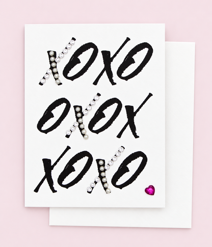 XOXOXOXO Heart Greeting Card with white envelope on a pale pink background